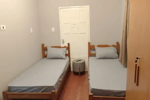 Quarto de acomodação com camas individuais e roupa de cama clara