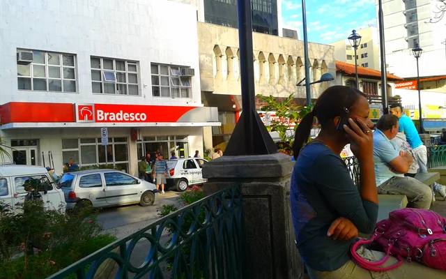 Praça com pessoas e prédios ao fundo em Barbacena