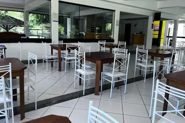 Refeitório com mesas e cadeiras e janelas amplas em unidade da rede